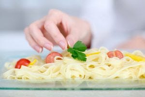 Closeup-on-woman-putting-parsley-on-pasta-dish-300x200.jpg
